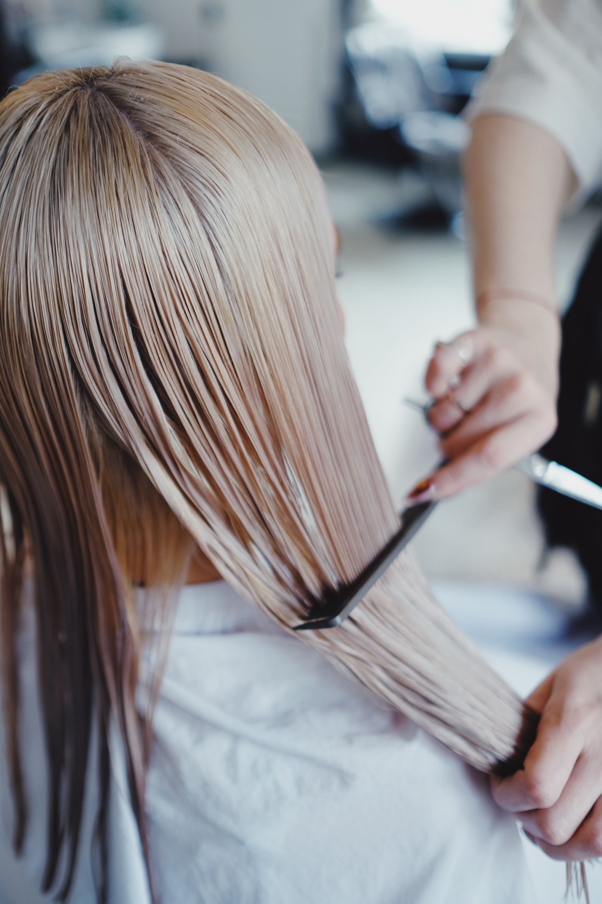 Detalle editorial de cabello rubio trabajado con peine y tijeras.